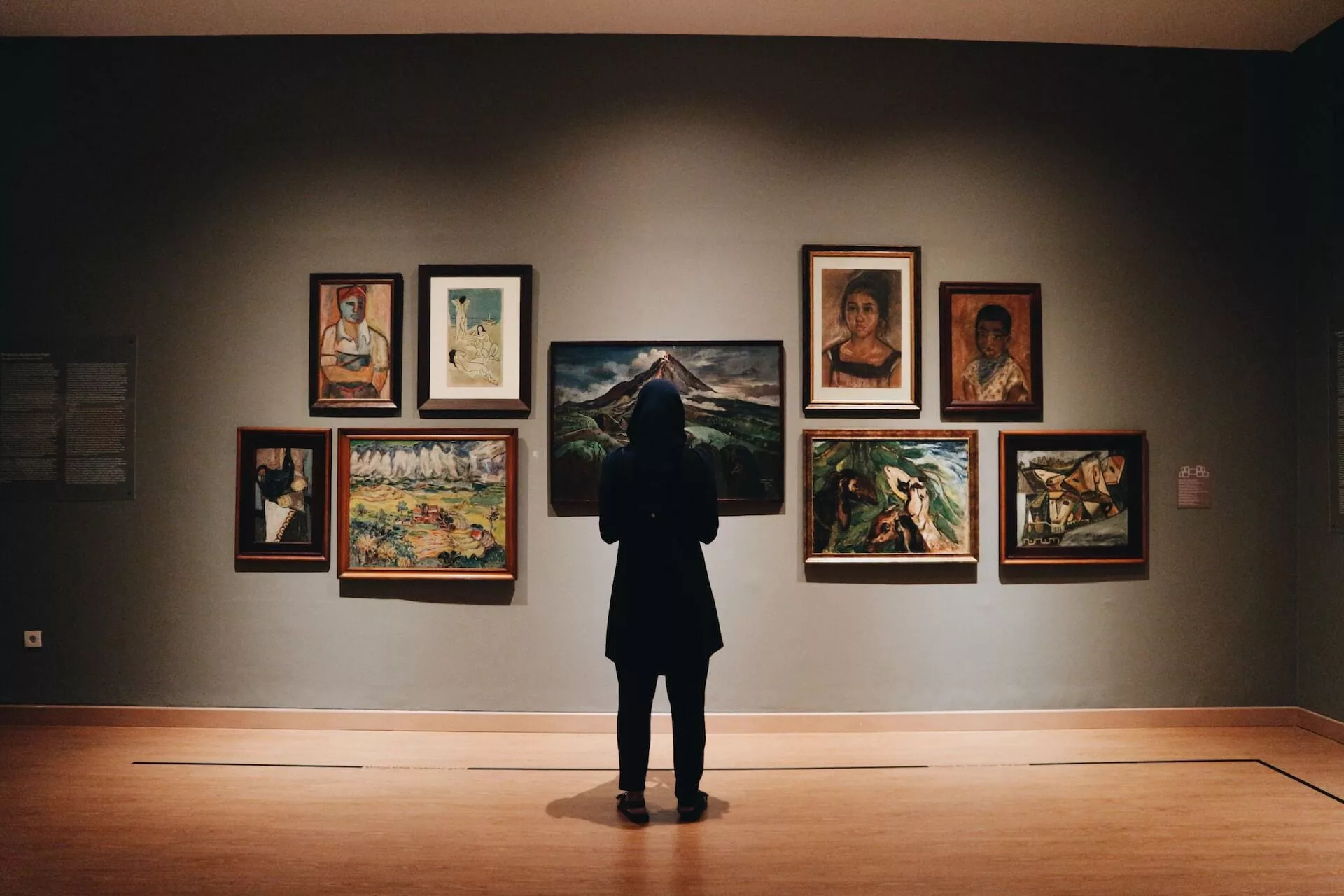 museum goer viewing paintings on a plain wall