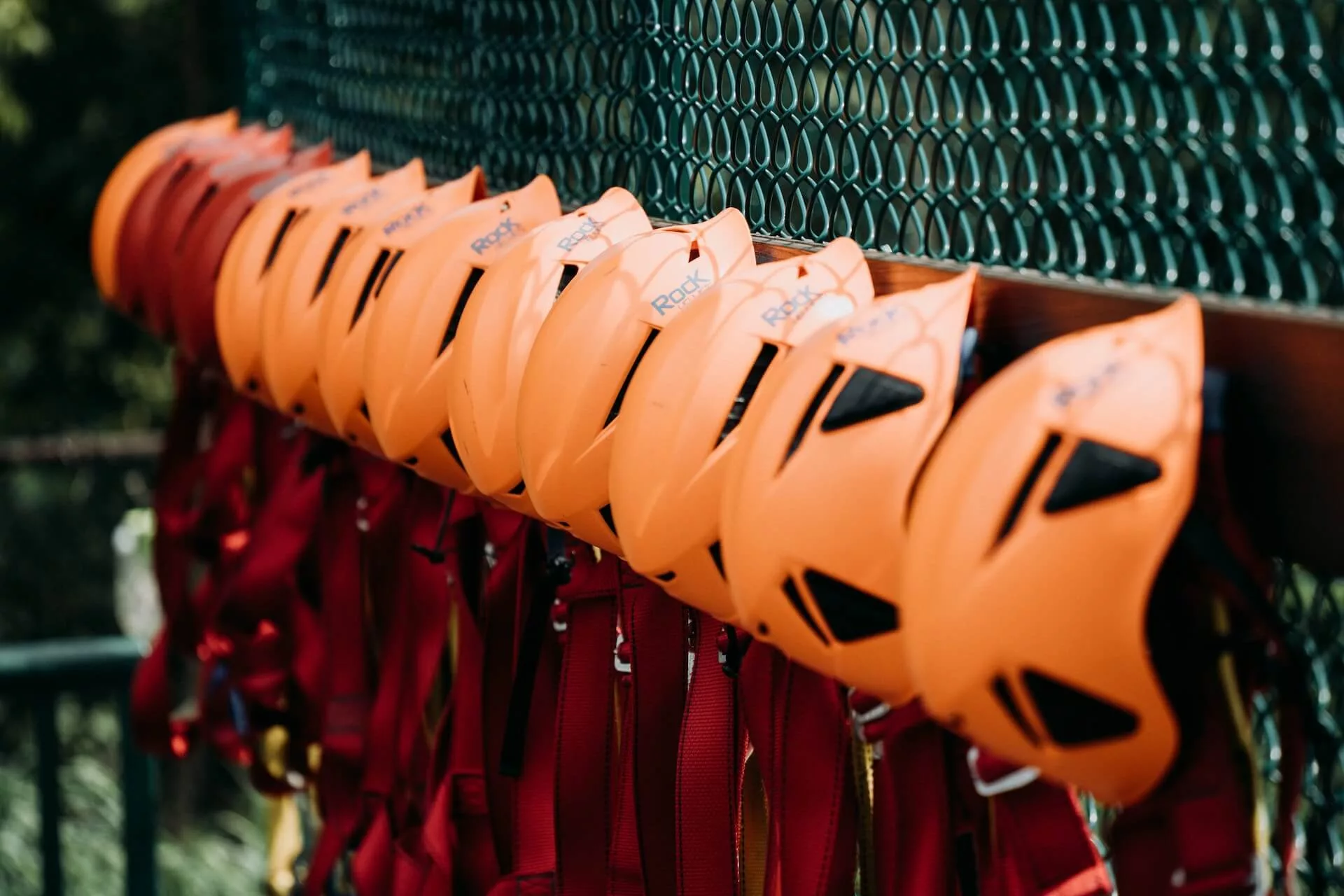 ziplining harnesses and helmets hung up on a wire fence