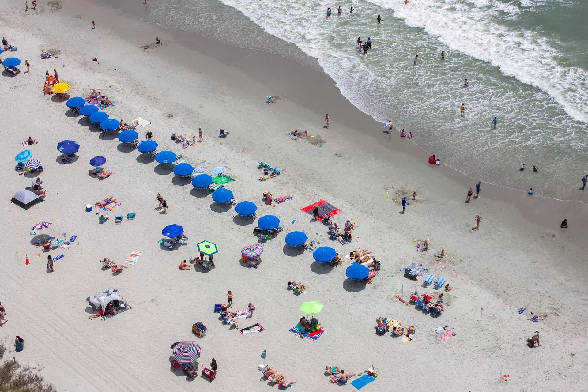 crowded myrtle beach with line of blue umbrellas